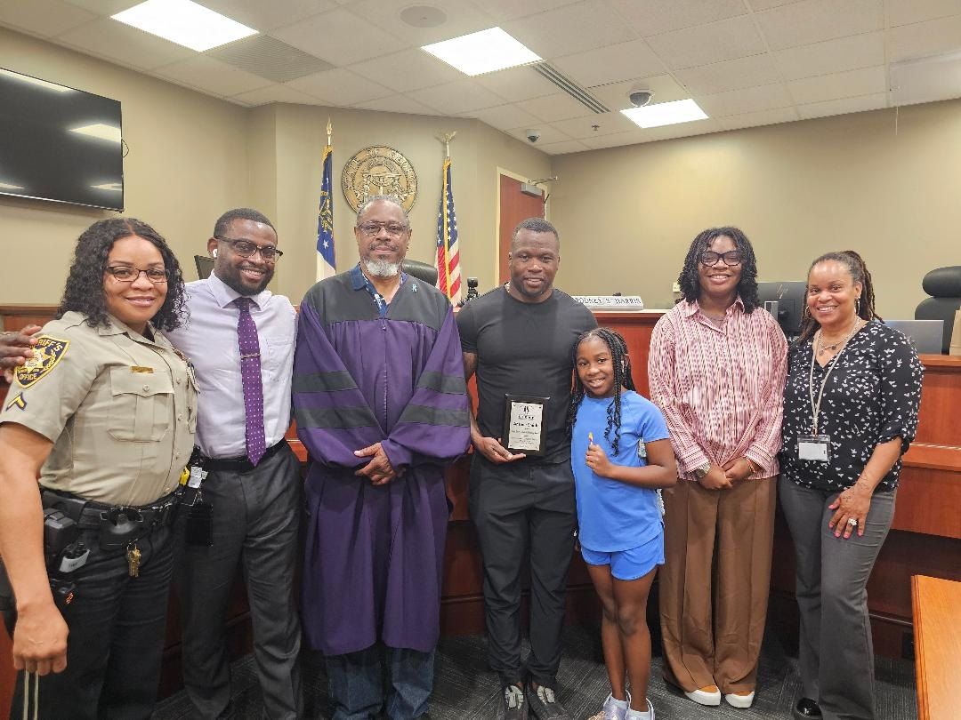 Community partners, officials and a child gathered in a courtroom.